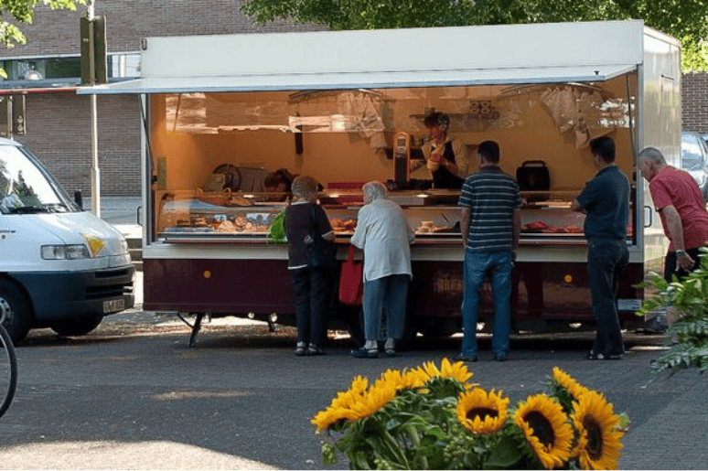 Mehrere Menschen stehen vor einem mobilen Verkaufsstand